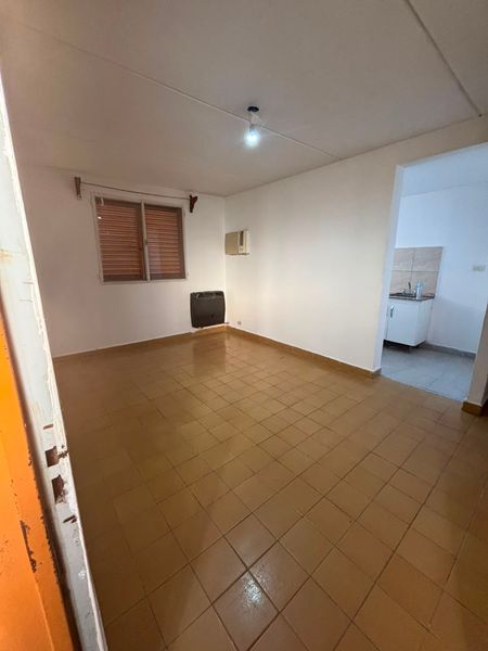 Living del departamento con ventana, piso cerámico y vista a la cocina